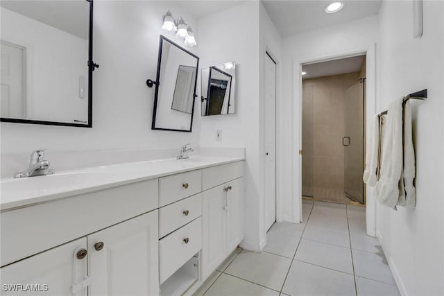 bathroom featuring a sink, tile patterned floors, a shower stall, double vanity, and baseboards