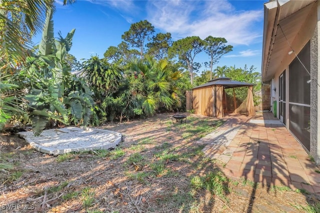 view of yard featuring a gazebo, fence, and an outdoor fire pit