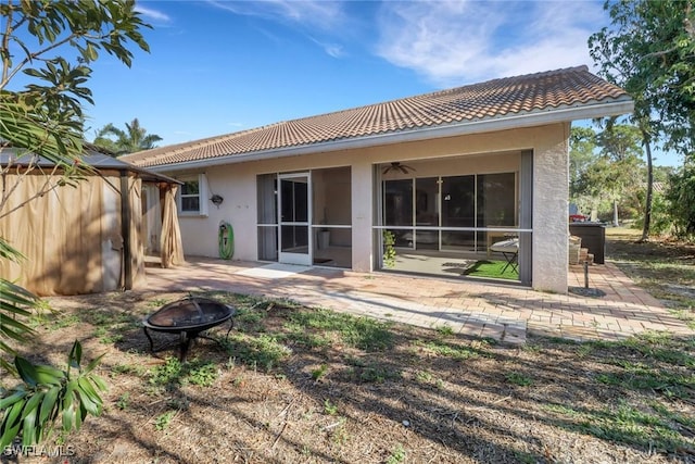 rear view of house featuring a fire pit, stucco siding, a tile roof, and a gazebo