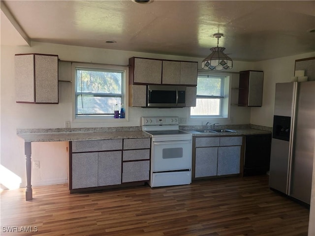 kitchen with a sink, dark wood-style flooring, hanging light fixtures, and appliances with stainless steel finishes