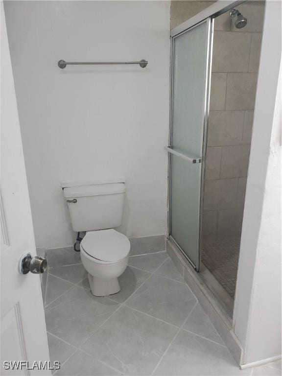 bathroom with toilet, tile patterned flooring, and a stall shower