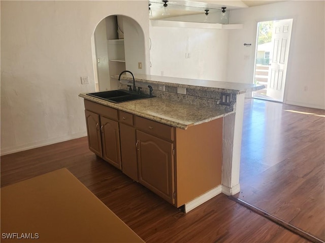 kitchen with dark wood-style flooring, baseboards, arched walkways, and a sink