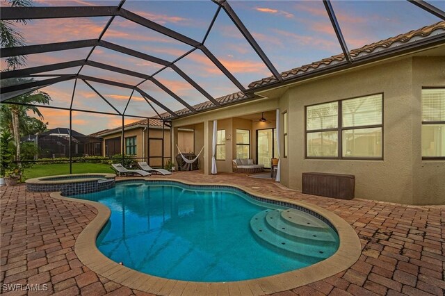 3454 Pacific Dr, Naples, FL 34119 - pool at dusk with a patio, a pool with connected hot tub, ceiling fan, and glass enclosure