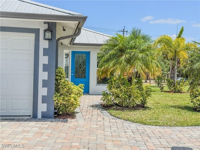 168 Village Cir Unit 9, Labelle, FL 33935 - entrance to property with stucco siding, a standing seam roof, a lawn, a garage, and metal roof