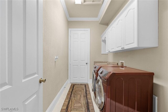 clothes washing area with cabinet space, crown molding, washer and clothes dryer, and baseboards