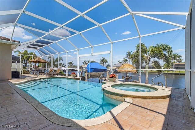 view of swimming pool with a patio, a lanai, a pool with connected hot tub, and a water view