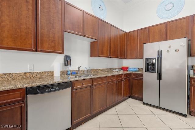 kitchen featuring stone countertops, ornamental molding, light tile patterned flooring, a sink, and stainless steel appliances
