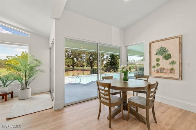 dining room featuring light wood finished floors, plenty of natural light, and lofted ceiling