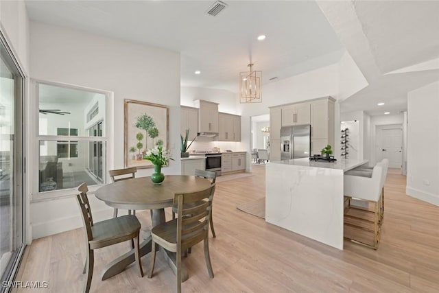 dining space with an inviting chandelier, light wood-type flooring, visible vents, and recessed lighting