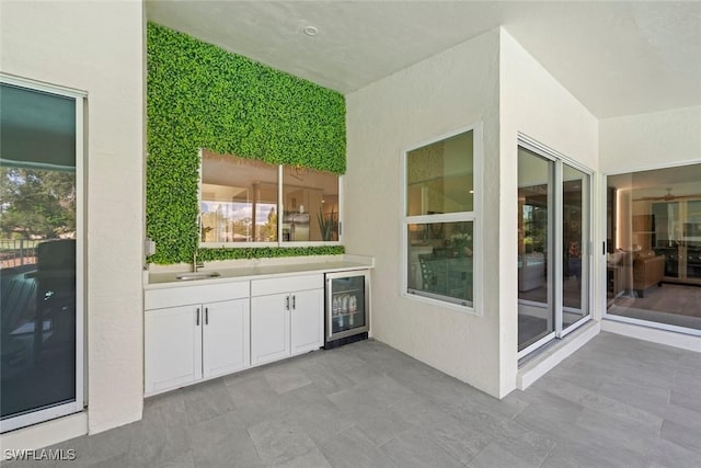 view of patio / terrace featuring beverage cooler, an outdoor kitchen, and a sink