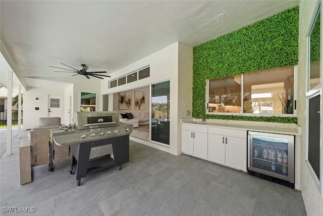 view of patio with a ceiling fan, an outdoor kitchen, a sink, and wine cooler