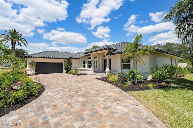 view of front of house featuring a tiled roof, stucco siding, decorative driveway, and a garage