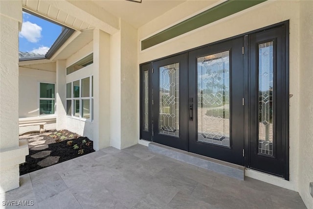 property entrance featuring a patio area, stucco siding, and french doors