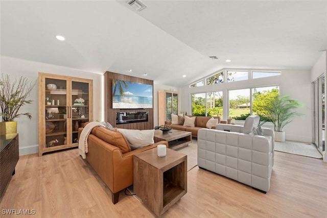 living area with baseboards, visible vents, light wood-style flooring, and lofted ceiling