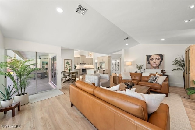 living room featuring lofted ceiling, light wood-type flooring, and visible vents