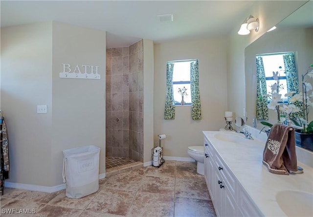 2128 SW 28th Ln, Cape Coral, FL 33914 - bathroom with a sink, toilet, double vanity, baseboards, and a tile shower