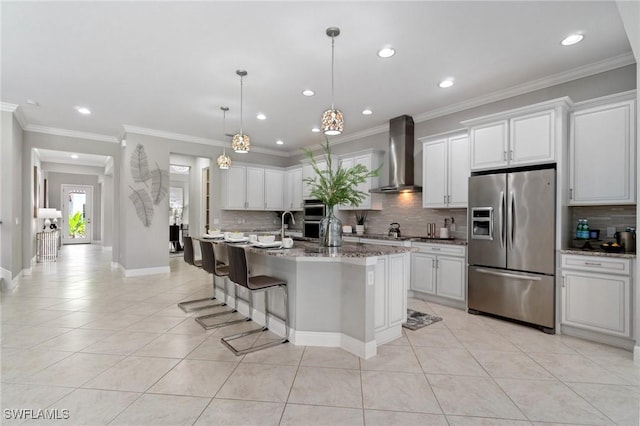4437 Tamarind Way, Naples, FL 34119 - kitchen featuring stainless steel appliances, wall chimney range hood, decorative backsplash, light tile patterned floors, and white cabinetry