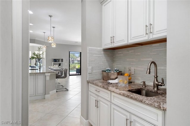 4437 Tamarind Way, Naples, FL 34119 - kitchen with a sink, backsplash, light tile patterned flooring, white cabinetry, and light stone counters