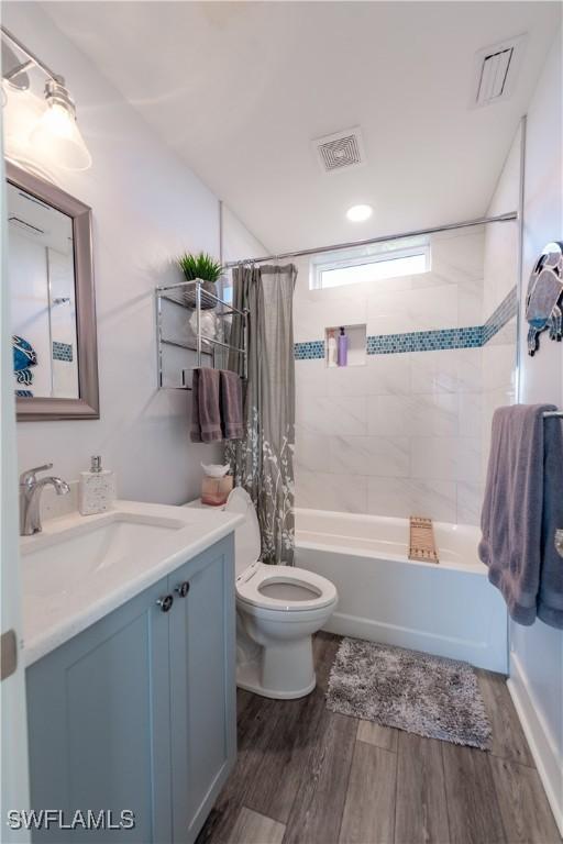 full bath featuring shower / bath combo, toilet, wood finished floors, and vanity