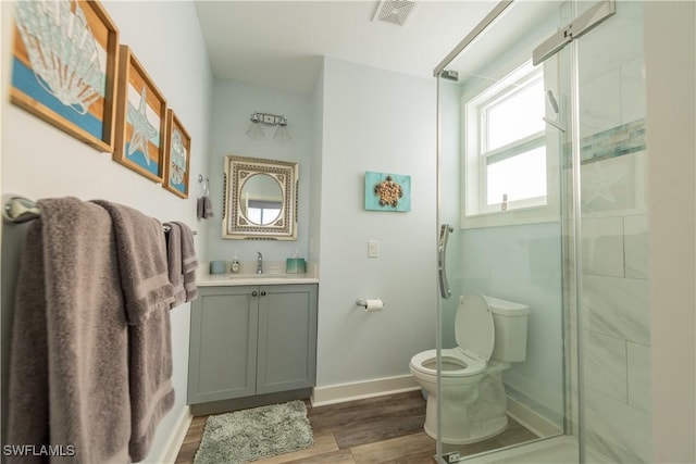 bathroom with wood finished floors, toilet, a stall shower, baseboards, and vanity