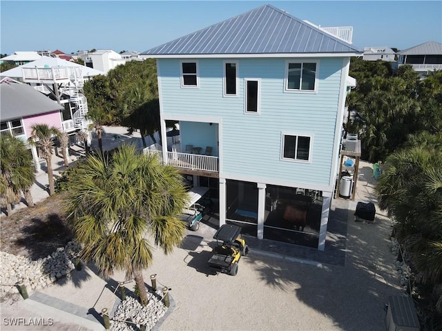 back of house featuring a patio area, metal roof, and a balcony
