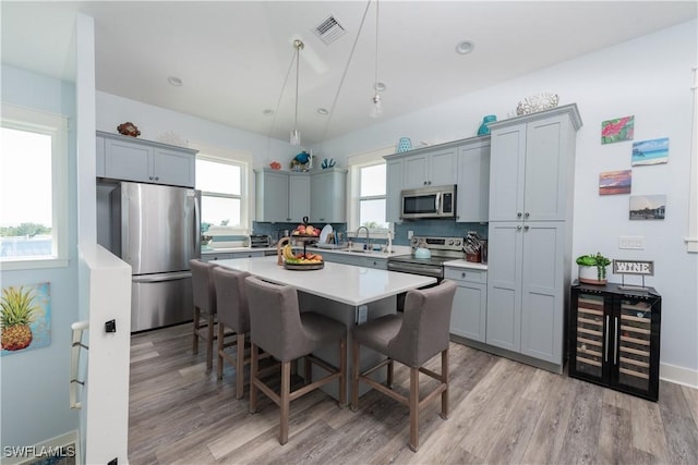 kitchen featuring stainless steel appliances, light wood finished floors, a breakfast bar, and a center island