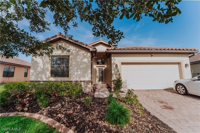 view of front of property featuring a tile roof, stucco siding, driveway, and a garage