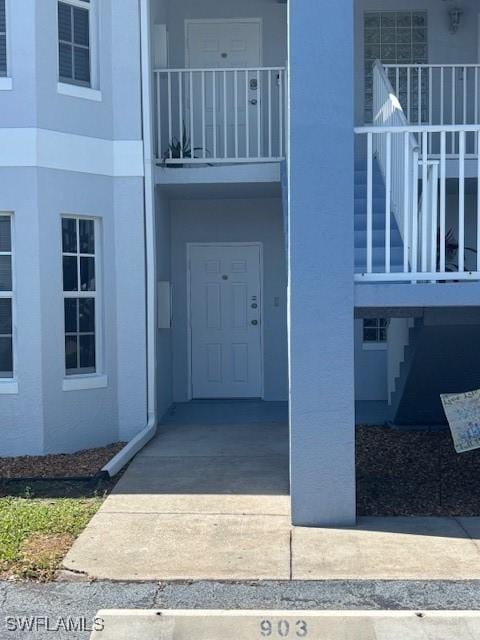 view of exterior entry with a balcony and stucco siding