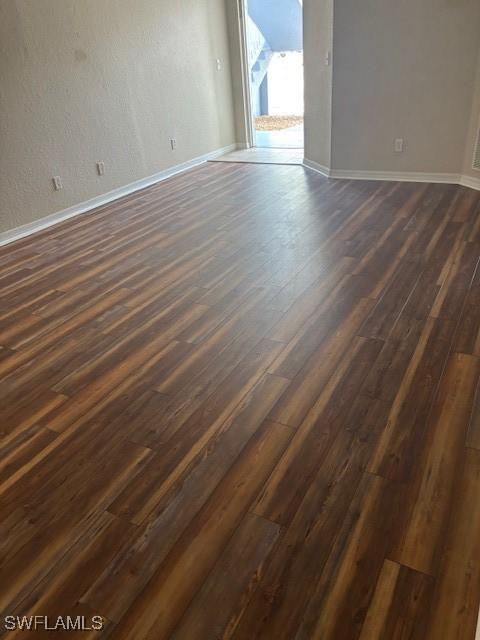empty room with baseboards and dark wood-style floors