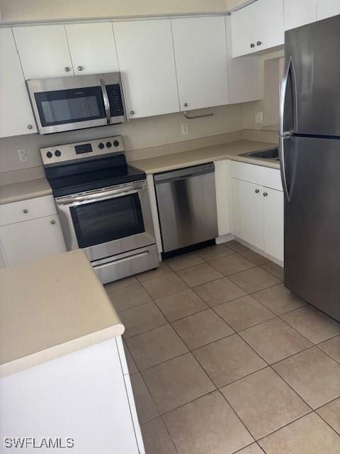 kitchen with appliances with stainless steel finishes, white cabinetry, light tile patterned flooring, and light countertops