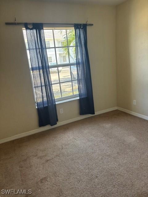 spare room featuring plenty of natural light, carpet floors, and baseboards