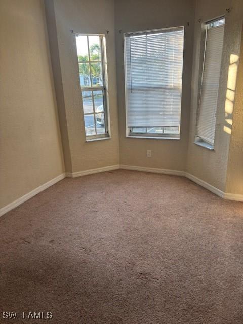 spare room featuring carpet and baseboards