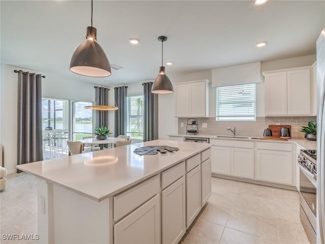 kitchen with a sink, stainless steel gas range oven, backsplash, and plenty of natural light