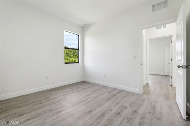 unfurnished room with light wood-style floors, visible vents, and baseboards