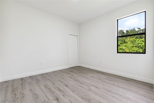 spare room featuring light wood-type flooring and baseboards