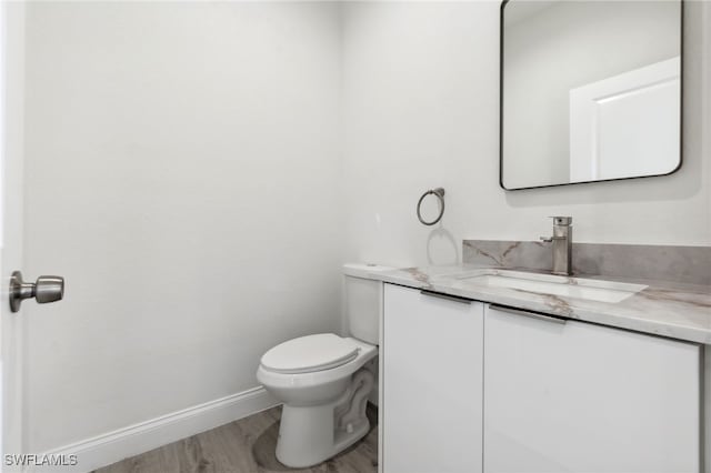 bathroom with vanity, toilet, baseboards, and wood finished floors