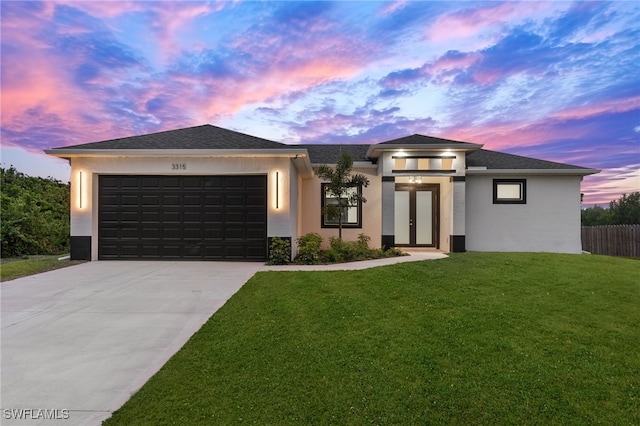 prairie-style home featuring concrete driveway, a front yard, stucco siding, and an attached garage