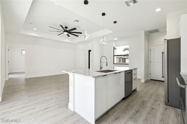 kitchen with a sink, a tray ceiling, white cabinets, visible vents, and appliances with stainless steel finishes