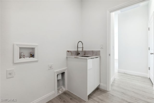 laundry area featuring a sink, laundry area, hookup for an electric dryer, light wood-style flooring, and baseboards