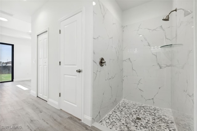bathroom with a marble finish shower and wood finished floors