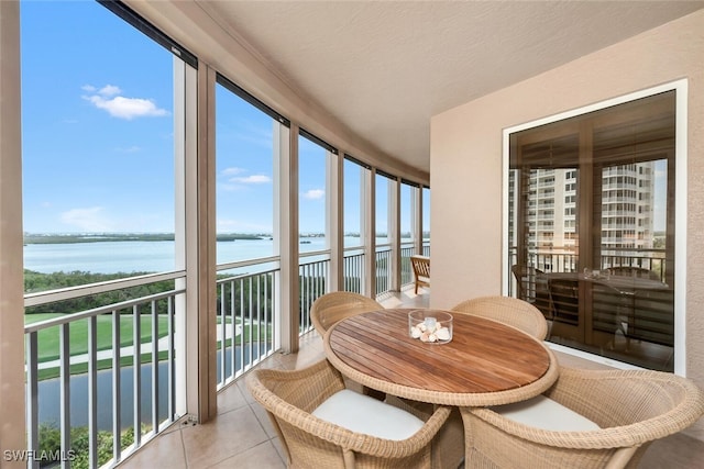 sunroom / solarium featuring plenty of natural light, a water view, and tile patterned flooring