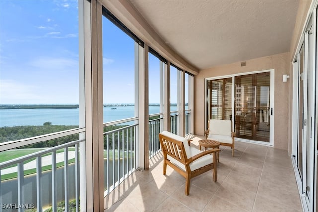 sunroom / solarium with a wealth of natural light, a water view, tile patterned flooring, and a textured ceiling