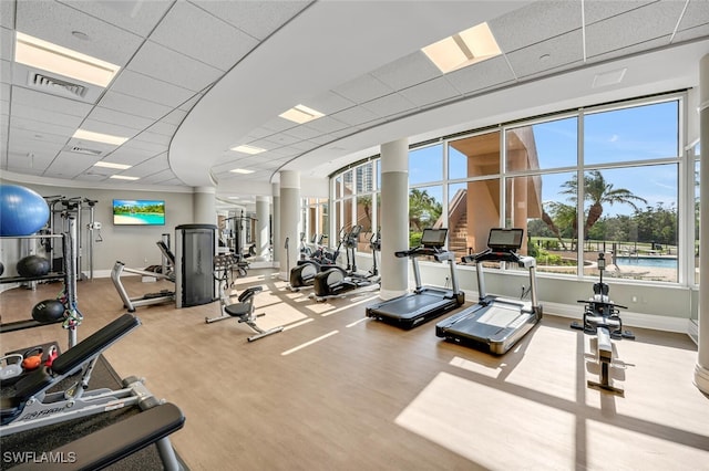 exercise room featuring wood finished floors, visible vents, baseboards, and a paneled ceiling