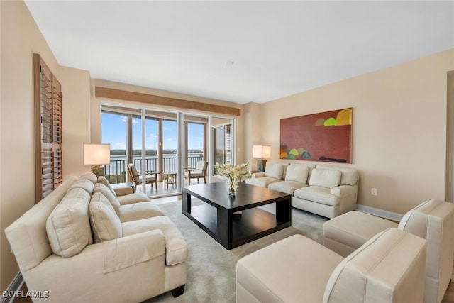 carpeted living area with a water view and baseboards
