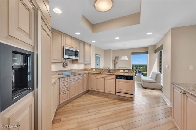 kitchen with paneled dishwasher, a sink, stainless steel microwave, a peninsula, and black electric stovetop