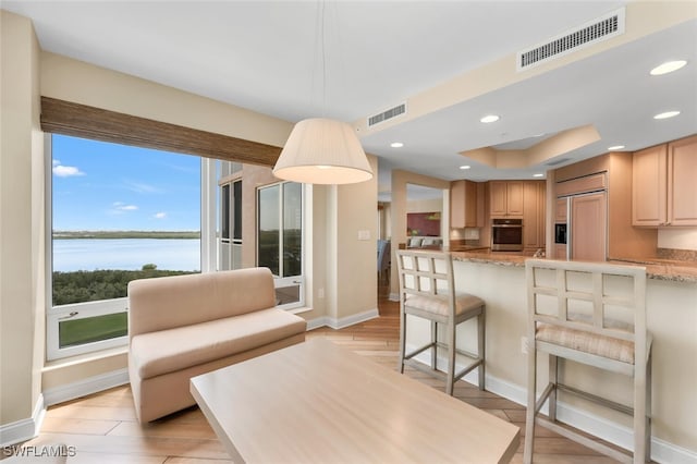 living room featuring a water view, baseboards, visible vents, and recessed lighting
