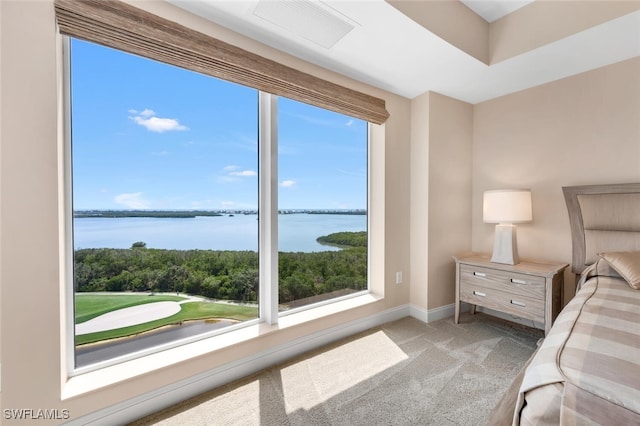 bedroom featuring light colored carpet, multiple windows, a water view, and visible vents