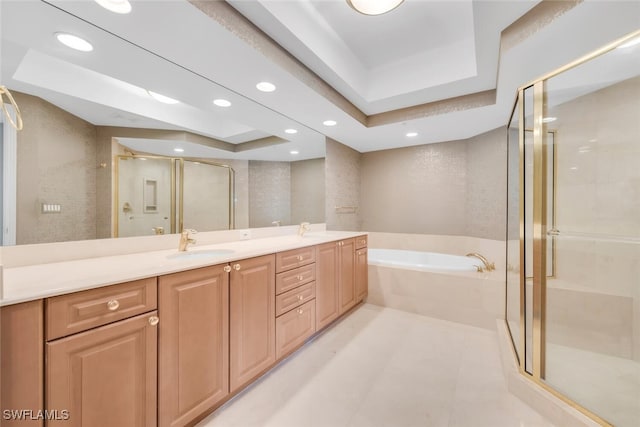full bath with double vanity, a raised ceiling, a garden tub, and a shower stall
