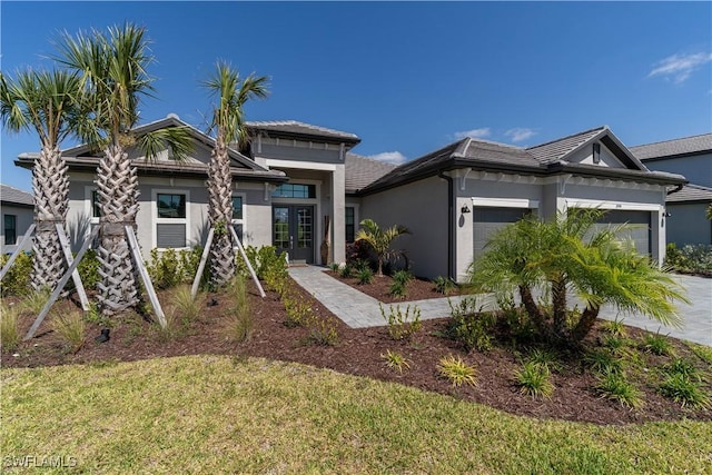 view of front of property with a garage, a tiled roof, stucco siding, concrete driveway, and a front lawn