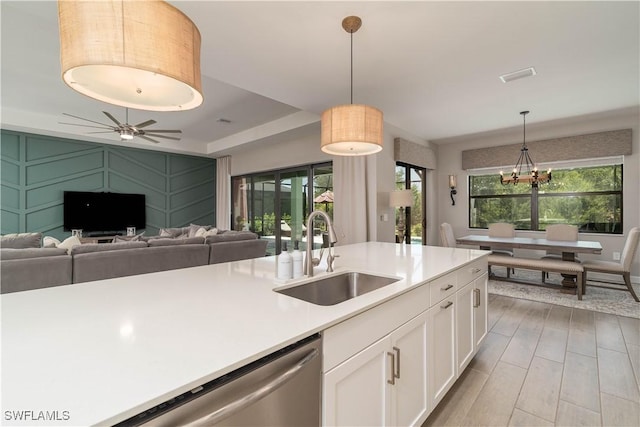 kitchen featuring dishwasher, visible vents, a sink, open floor plan, and white cabinets